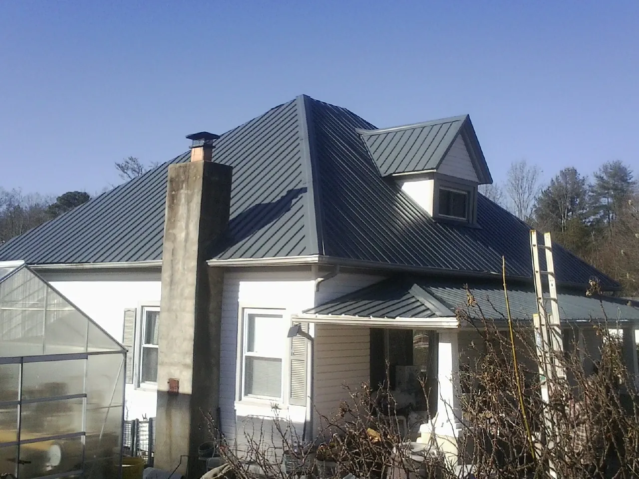 Dark blue standing seam metal roof on a white farmhouse with dormer — Slate & Tile Roof Repair by Roofing Brothers in Boone Grove