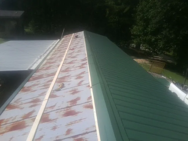 Old rusted panels beside newly installed green metal roofing — Wind Damage Roof Repair by Roofing Brothers in Boone Grove