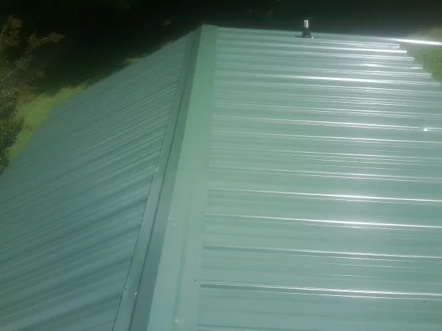 New green metal panels meeting at the ridge of a roof — Flat Roof Repair work by our crew in Boone Grove