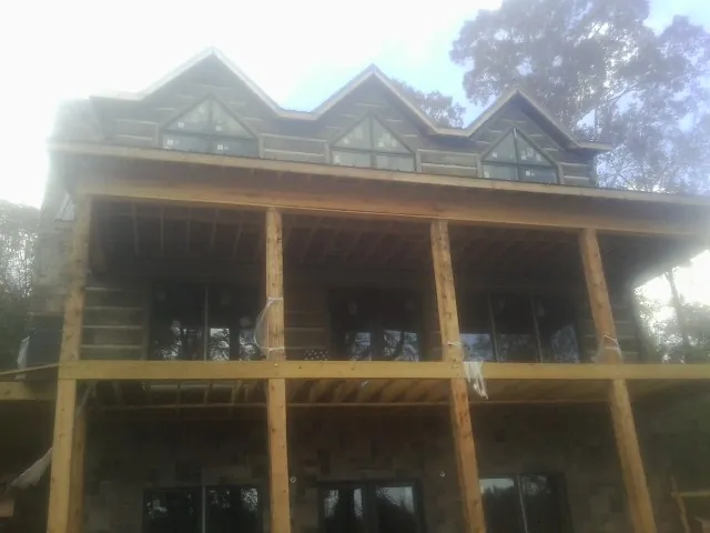 Dormers and porch framing on a large log home under construction — Roof Coating work by our crew in Boone Grove