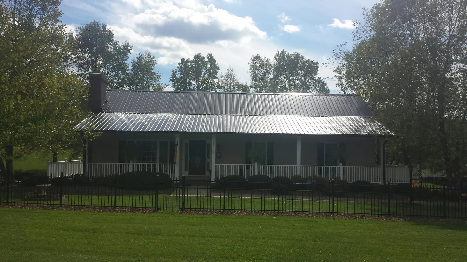 Gray metal roof on a brick ranch with a full width front porch — Gutter Guard Installation work by our crew in Boone Grove