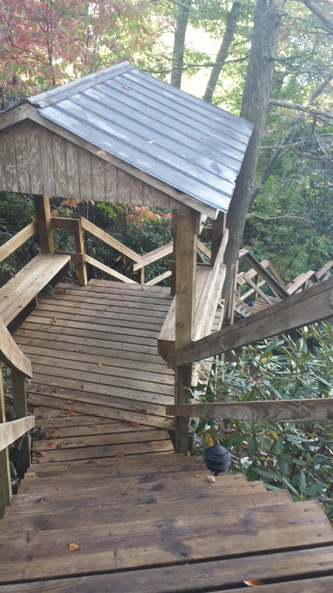 Metal roofed shelter over wooden steps on a wooded walkway — Skylight Repair & Installation work by our crew in Boone Grove