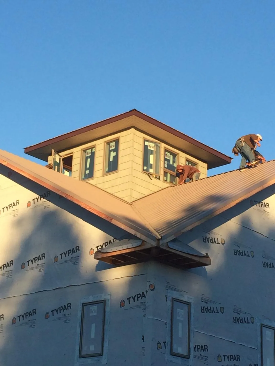 Roofers working around a rooftop cupola on a new metal roof at sunset — Roof Waterproofing in Boone Grove by Roofing Brothers